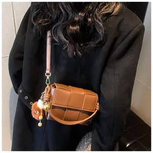 Detailed shot of a stylish brown woven leather crossbody bag worn on model, premium look.