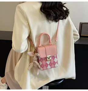 Pink plaid mini crossbody bag detail view with cute plush bunny charm and shoulder strap.