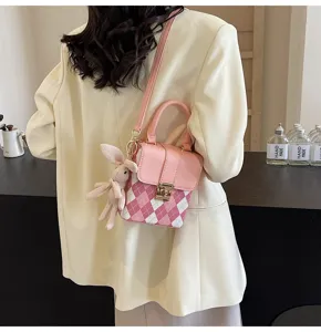 Detailed view of pink argyle mini crossbody bag with cute rabbit pendant and shoulder strap.