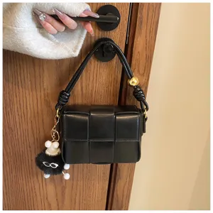 Black woven leather crossbody bag with metal sphere detail and cute charm for daily use.