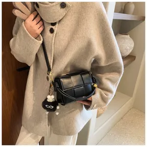 Stylish black woven leather shoulder bag with cute fluffy charm for women winter fashion outfit.
