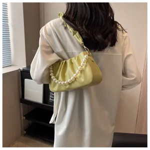 Detailed view of the stylish ruched yellow shoulder bag featuring a luxurious pearl chain strap.