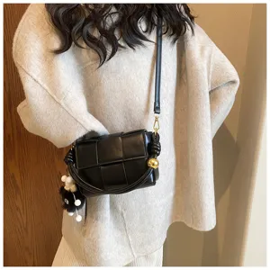 Black woven crossbody bag detail showing padded leather texture, chic knot and metal ball.