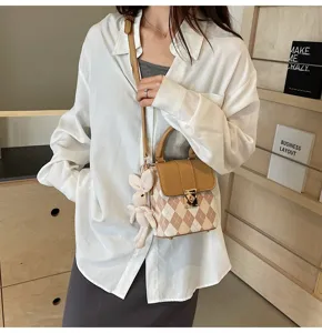Stylish diamond pattern mini crossbody bag with top handle and cute plush bunny charm detail.