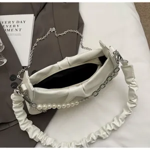 Detail view of white ruched shoulder bag with pearl chain strap and soft leather finish.