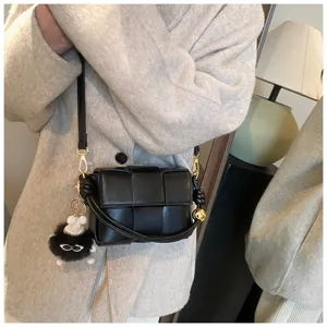 Black woven padded crossbody bag with chic metal hardware and fluffy cute charm for women.