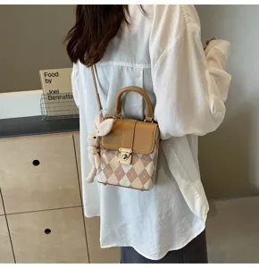 Detailed view of women crossbody bag with argyle pattern, brown flap and cute bunny pendant.