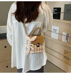 Detailed shot of trendy women argyle crossbody bag with cute rabbit pendant and handle.