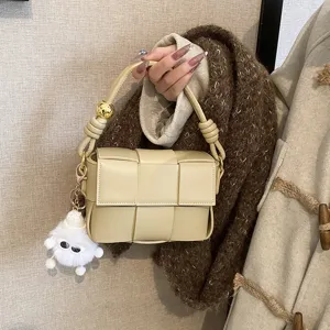 Chic woven leather shoulder bag for women, stylish crossbody handbag with plush charm.