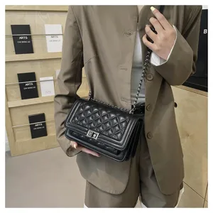 Detailed close-up shot of the black quilted chain shoulder bag worn by model, chic.