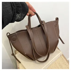 Detail shot of the brown leather tote bag with unique wing design and contrast white stitching.