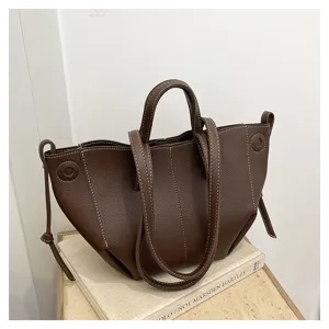 Detailed view of brown leather tote bag with stylish white stitching and slouchy wing design.