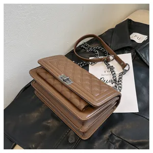 Detailed view of brown quilted shoulder bag with metal lock and chic chain strap design.