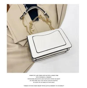 White shoulder bag with gold chain and black trim, stylish and elegant detail shot.