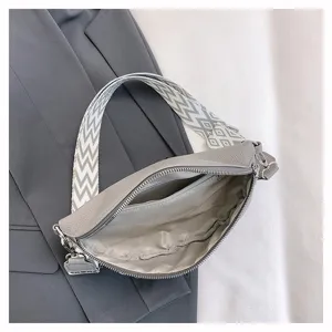 Détail intérieur du sac banane en cuir gris, large bandoulière géométrique et poche zippée.