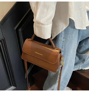 Gros plan détaillé et précis sur le sac à main en cuir marron élégant et ses ferrures dorées.