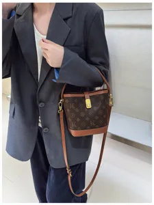 Detailed view of the retro luxury bucket bag with monogram print, leather trim and shoulder strap.