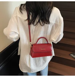 Vue détaillée du sac bandoulière rouge avec finition brillante et poignée chic.
