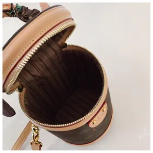 Vue detaillee du sac cylindrique marron vintage a monogramme avec fermeture eclair et foulard chic.