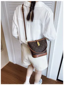 Detail shot of retro monogram bucket bag with classic pattern, brown leather trim and metal lock.