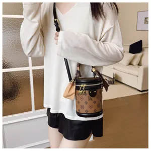 Chic sac seau cylindrique marron à monogramme avec poignée et bandoulière pour femmes.