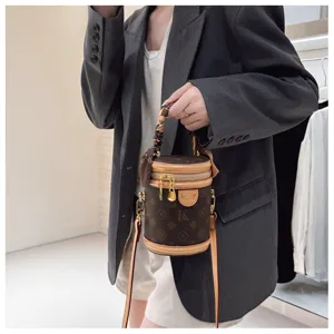 Sac bandoulière cylindrique monogrammé marron avec poignée et foulard élégant.