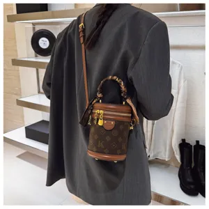 Vue détaillée du sac seau cylindrique rétro à monogramme avec poignée foulard et bandoulière.