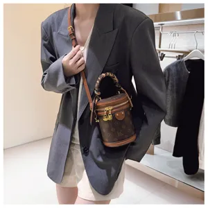 Vue détaillée du sac seau cylindrique vintage avec motif monogramme et foulard chic.