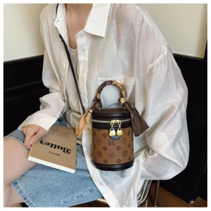 Sac seau cylindrique à motif monogramme vintage, poignée élégante et bandoulière chic.