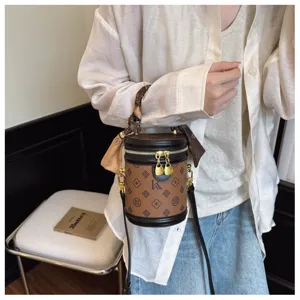 Chic sac seau cylindrique rétro pour femme, design monogramme élégant avec poignée et bandoulière.