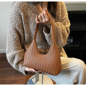 Vue détaillée du sac à aisselles marron tissé en croissant montrant une texture exquise.