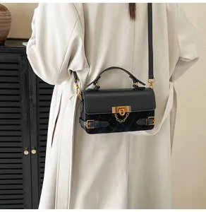 Detail view of a black quilted crossbody bag featuring elegant gold-tone hardware and buckle.