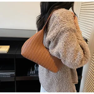 Vue détaillée élégante de sac porté épaule tressé marron en cuir texturé style croissant.