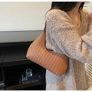 Vue détaillée d'un sac sous les bras en cuir tissé marron, forme hobo croissant élégante.