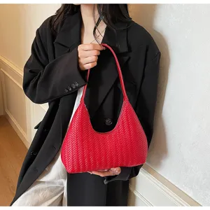 Vue détaillée du sac croissant tissé rouge sous le bras, montrant la texture en cuir.