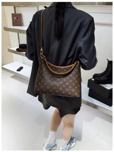 Detail shot of a stylish brown monogram shoulder bag worn by a model in a modern setting.