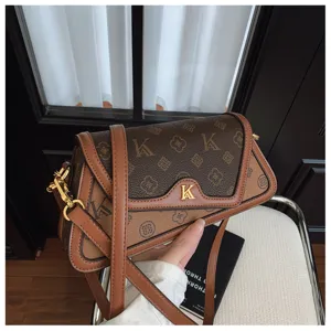 Stylish brown monogram shoulder bag for women, chic crossbody bag with metal logo and contrast trim.