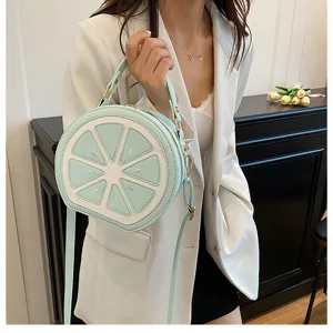 Dettaglio della borsa a tracolla verde menta a forma di limone, design rotondo.