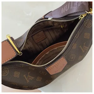 Detailed view of brown monogram crescent hobo crossbody bag with zipper and shoulder strap.