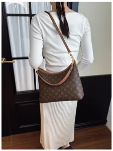 Detail shot of women's stylish brown monogram shoulder bag worn outdoors, daily commuter chic style.