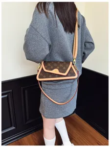 Detail shot of stylish brown monogram underarm shoulder bag with contrasting leather trim.