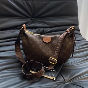Brown monogram crescent shoulder bag for women, stylish hobo crossbody bag with wide strap.
