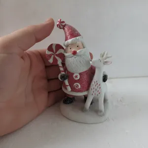 Detailed view of resin Santa Claus and reindeer figurine holding candy cane ornament.