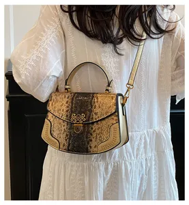 Detail view of stylish snakeskin pattern shoulder bag with gold hardware and clasp closure.