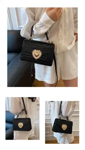 Borsa a tracolla nera con stampa coccodrillo e dettaglio di chiusura a cuore dorato elegante.
