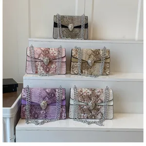 Sac à bandoulière pour femme motif serpent avec chaîne métal et fermoir tête d'animal.