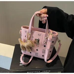 Pink leather bucket bag detail view with cute bear print pattern and stylish gold hardware.