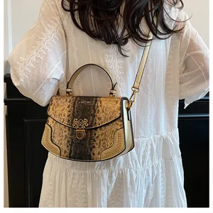 Detail view of the stylish gold snakeskin crossbody bag with metal lock and handle.