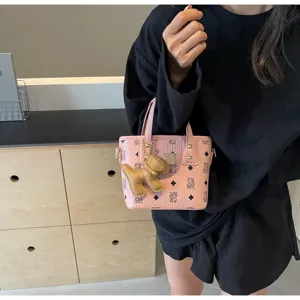 Pink bucket bag detail shot showing cute dog charm and classic monogram pattern design.