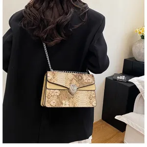 Sac à bandoulière chic en similicuir serpent avec chaîne et fermoir tête de serpent.
